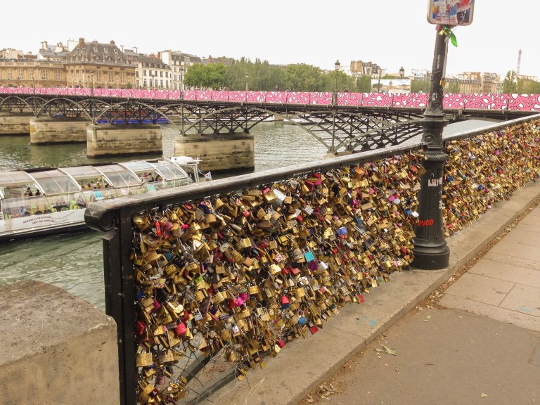 Love locks by the river. The boarded-up Pont des Arts can be seen in the background.